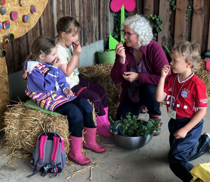 Eine Frau und drei Kinder riechen an Kräutern