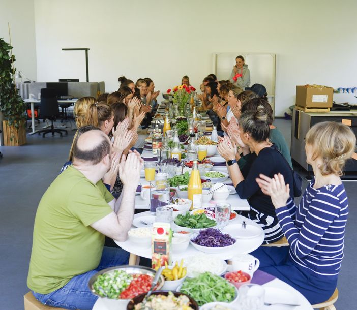 Menschen an einer langen gedeckten Tafel im Büro der Sarah Wiener Stiftung
