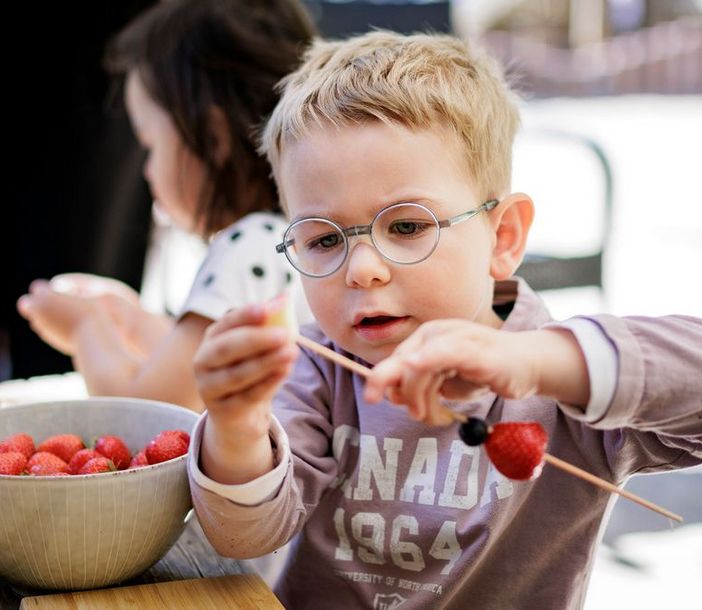 Junge spießt Obst auf Spieß