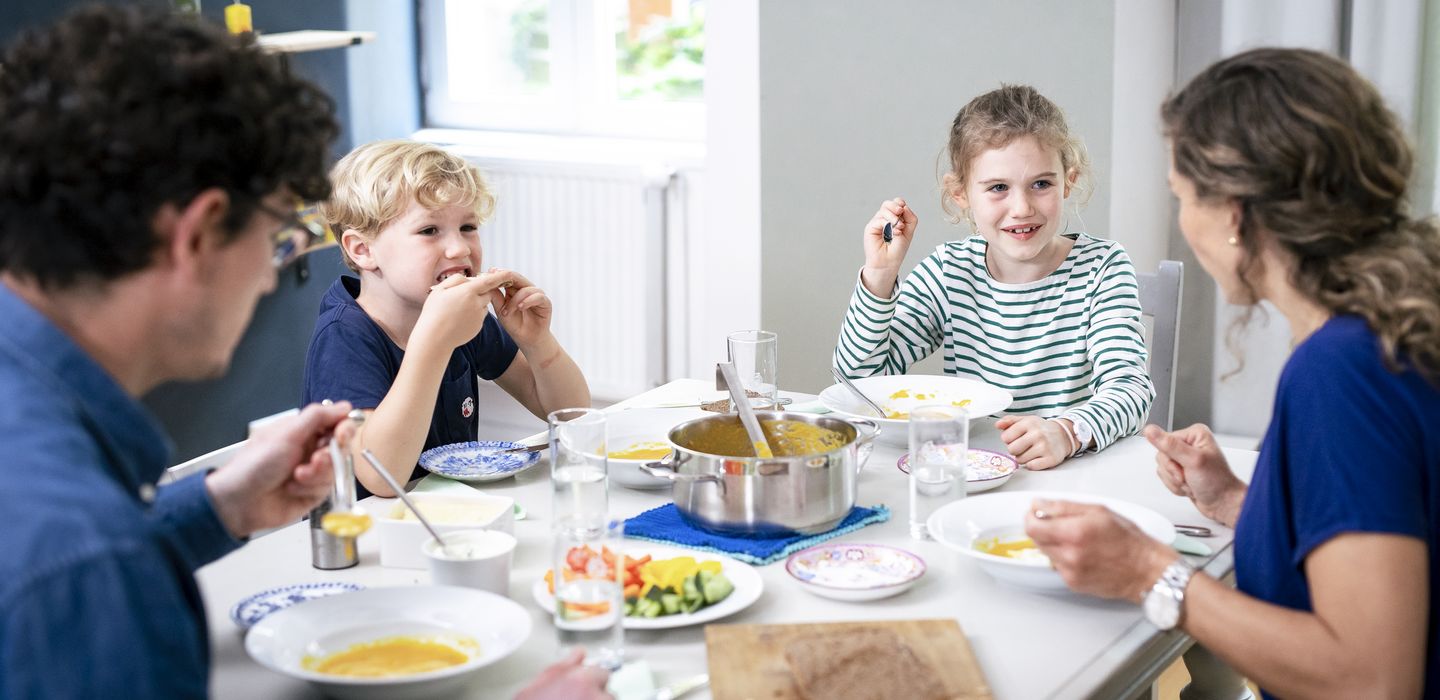 Zwei Erwachsene und zwei Kinder sitzen am Esstisch