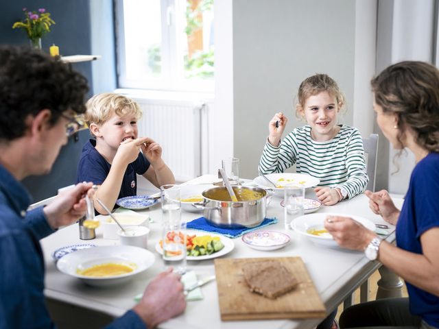 Zwei Erwachsene und zwei Kinder sitzen am Esstisch
