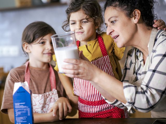 Mutter misst mit zwei Töchtern Milch in der Küche ab