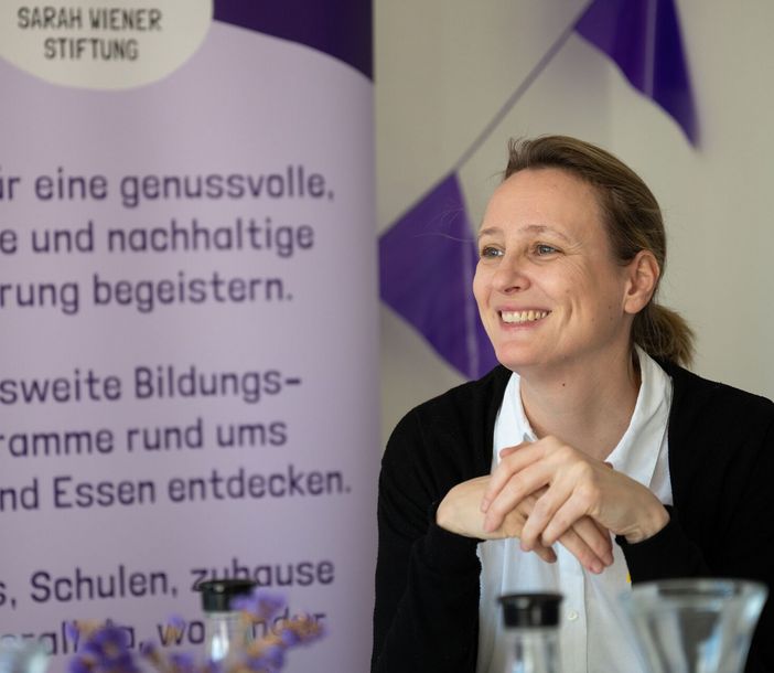 Christina Mersch vor einem Plakat der Sarah Wiener Stiftung