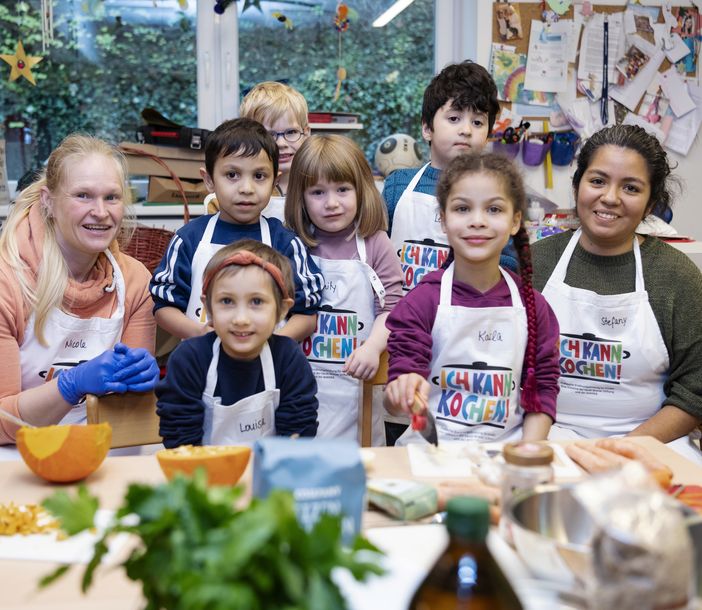 Zwei Lehrerinnen mit einer Gruppe von Kindern in einer Küche