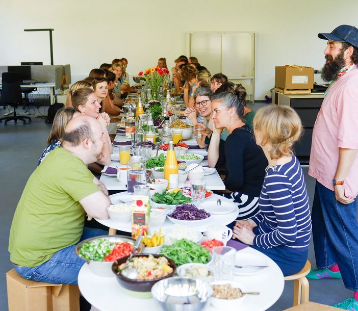 Erwachsene sitzen an einem Tisch und reden und essen miteinander