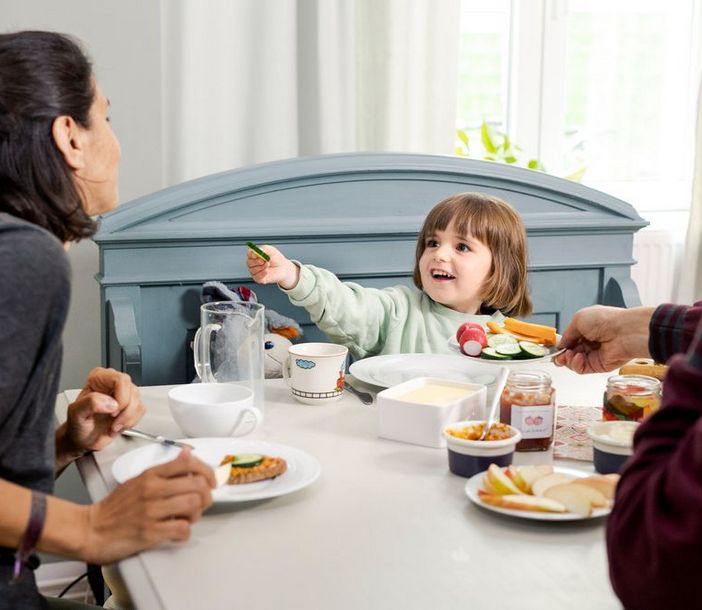 Tochter bietet ihrer Mutter essen am Esstisch an