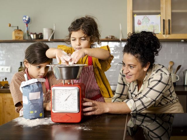 Mutter wiegt Mehl mit zwei Kindern in der Küche