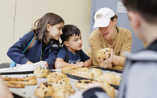 Eine Bäckerin betrachtet ein süßes Brötchen mit zwei Kindern 