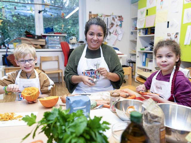 Zwei Kinder und eine Erwachsene höhlen Kürbis aus