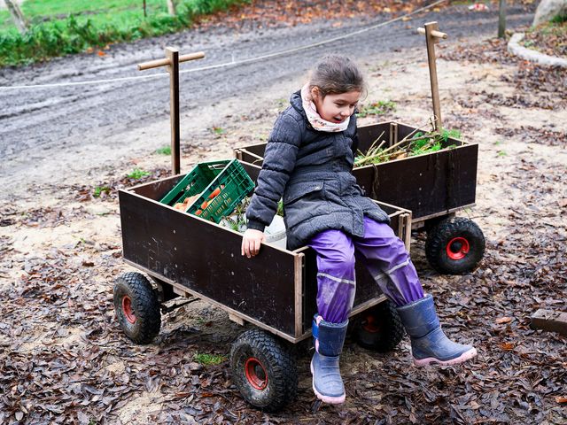 Ein Kind sitzt auf einem Bollerwagen mit Gemüse