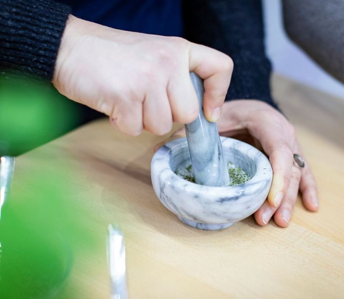 Eine Hand mörsert Kräutersalz