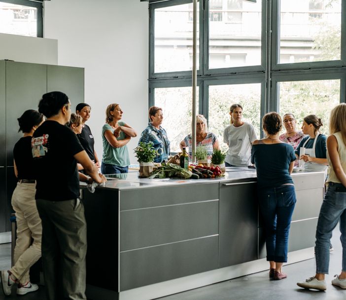 12 Personen stehen um eine Kücheninsel