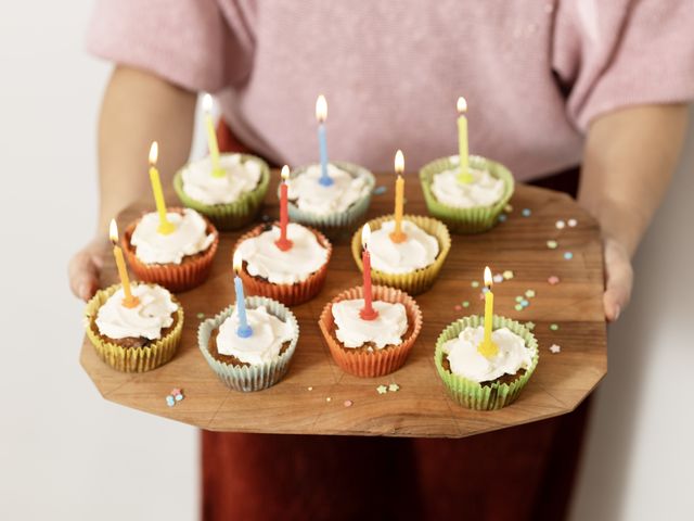Muffins mit bunten Kerzen auf einem Holzbrett 