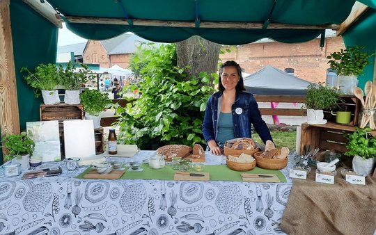 Stand beim Sommerfest auf Gut Kerkow: Eine Frau steht hinter einem dekorierten Tisch