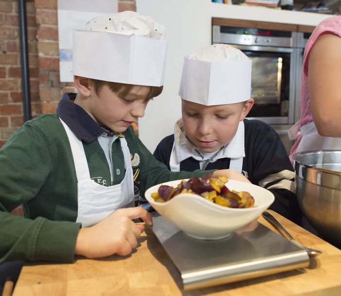 Zwei Kinder gucken in eine Schüssel auf einer Waage