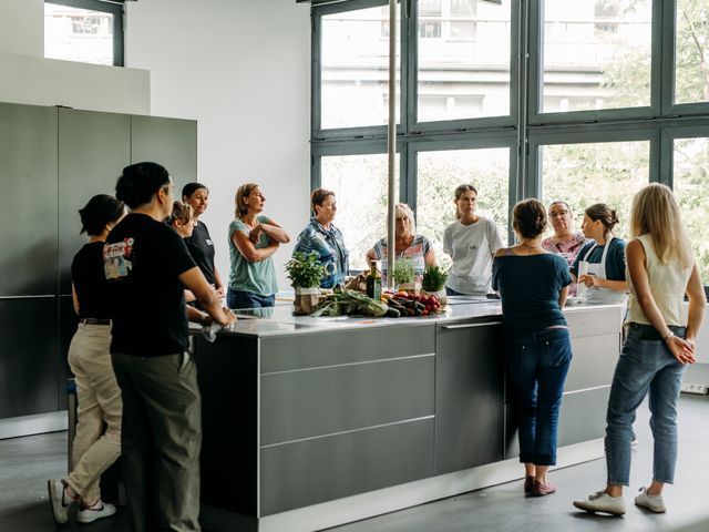 12 Personen stehen um eine Kücheninsel