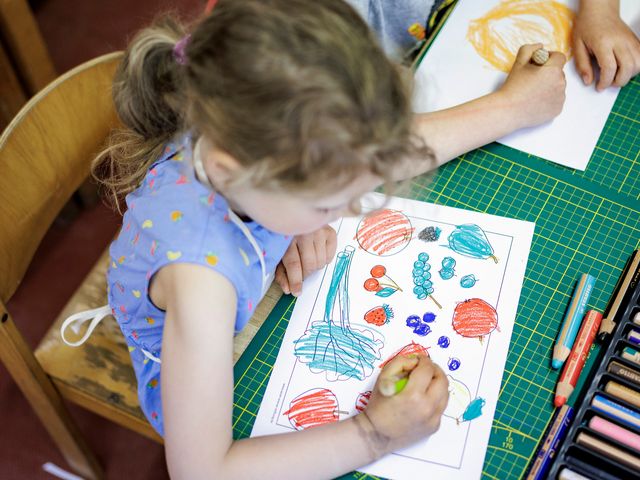 Mädchen gestaltet ein Tischset mit bunten Farben.
