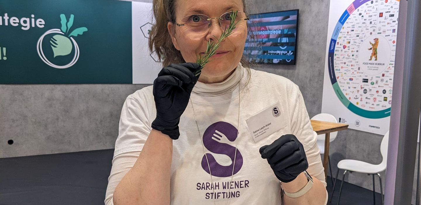 Eine Frau schnuppert an einem Zweig Rosmarin