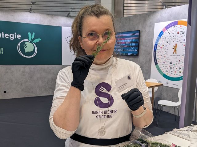 Eine Frau schnuppert an einem Zweig Rosmarin