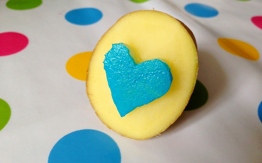 Ein Kartoffelstempel in Herzform mit blauer Farbe 